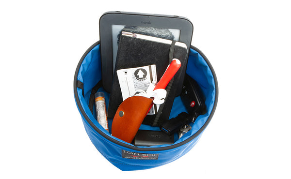 A Large Travel Tray holding a pocket notebook, Nook e-reader, headphones, travel toothbrush, keys, small portable charger, and chapstick.